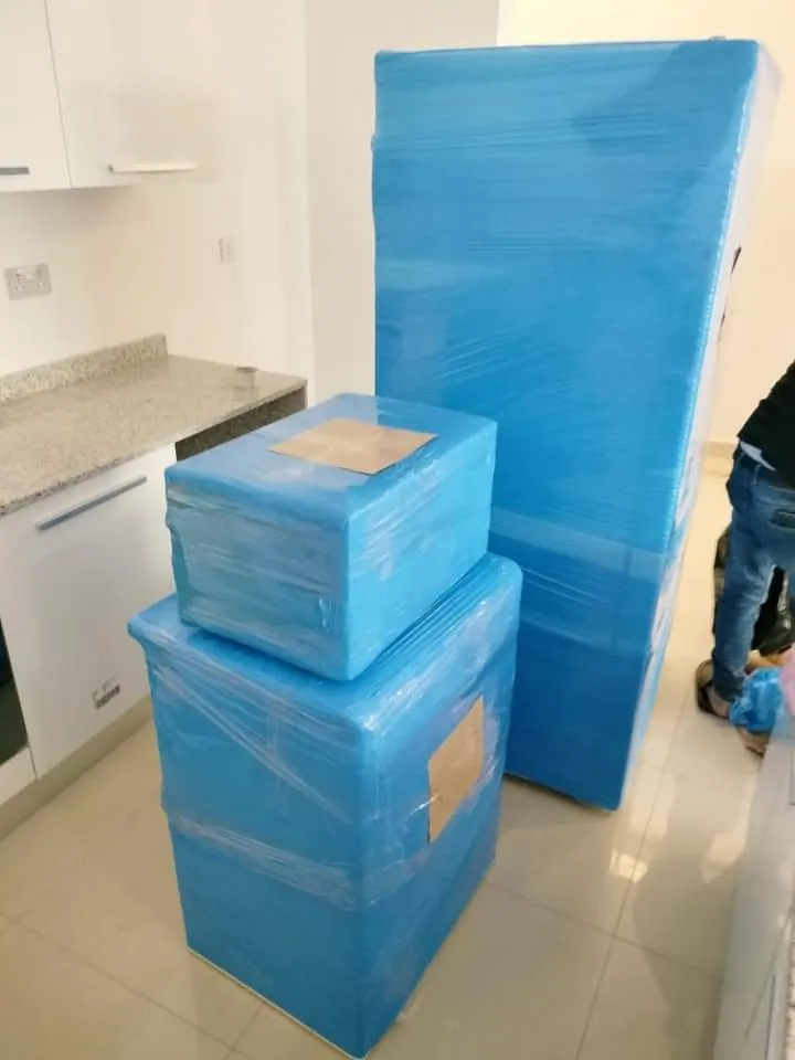 كراتين نقل عفش وقطع أثاث مغلفة بالنايلون الأزرق داخل مطبخ