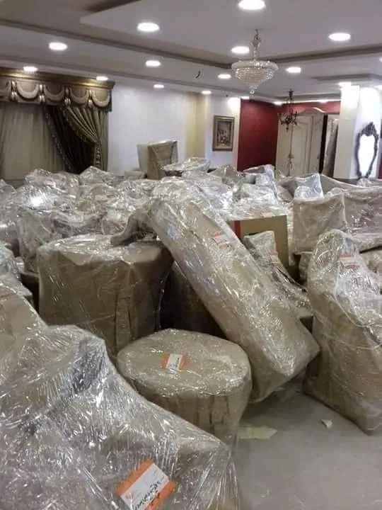قاعة مليئة بقطع أثاث مغلفة بالنايلون قبل تحميلها
