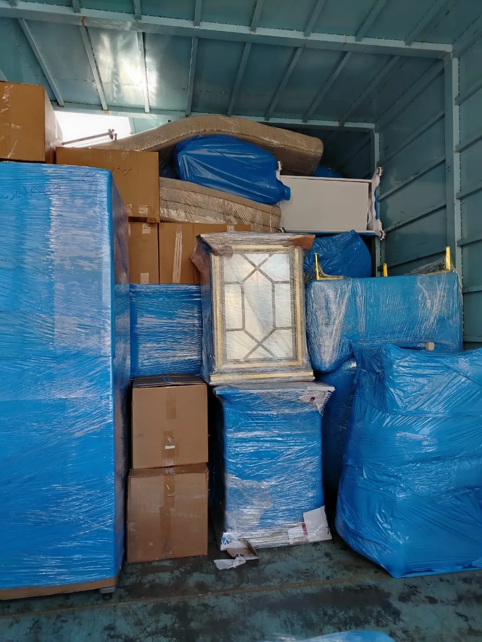 نقل عفش خارج الرياض: أثاث مغلف بالنايلون الأزرق وكراتين مرصوصة داخل صندوق النقل